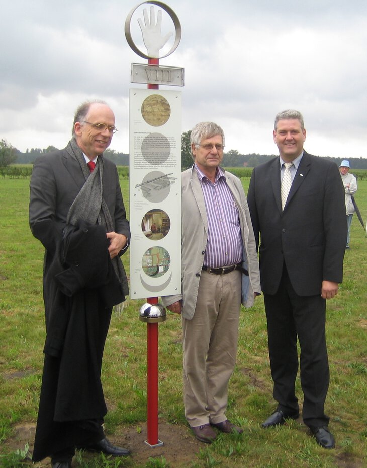 Das Bild zeigt eine Tafel des neuen Lehrpfades im Römerlager Anreppen. Von links nach Rechts: Dr. Kees Peterse, Dr. Johann-Sebastian Kühlborn und Bürgermeister Werner Peitz.