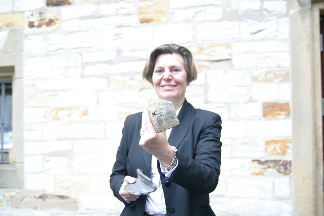 Wissenschaftlerin mit Leib und Seele: Sveva Gai zeigt vor dem Josefs-Haus am Busdorfwall, wo die Stadtarchäologie beheimatet ist, die Überreste zweier Krüge. Sie wurden jüngst bei Grabungen im Stadtkern geborgen. 